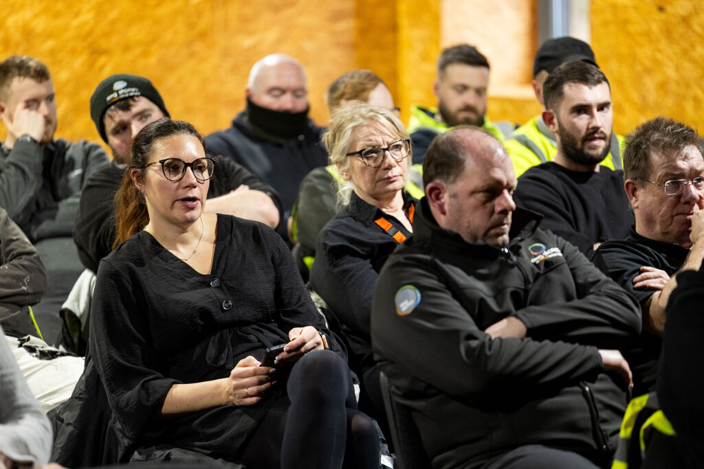 Group of adult learners seated closely during a face‑to‑face training session, listening to course content.
